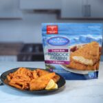 Plate of English Style Battered Haddock and fries presented next to packaging