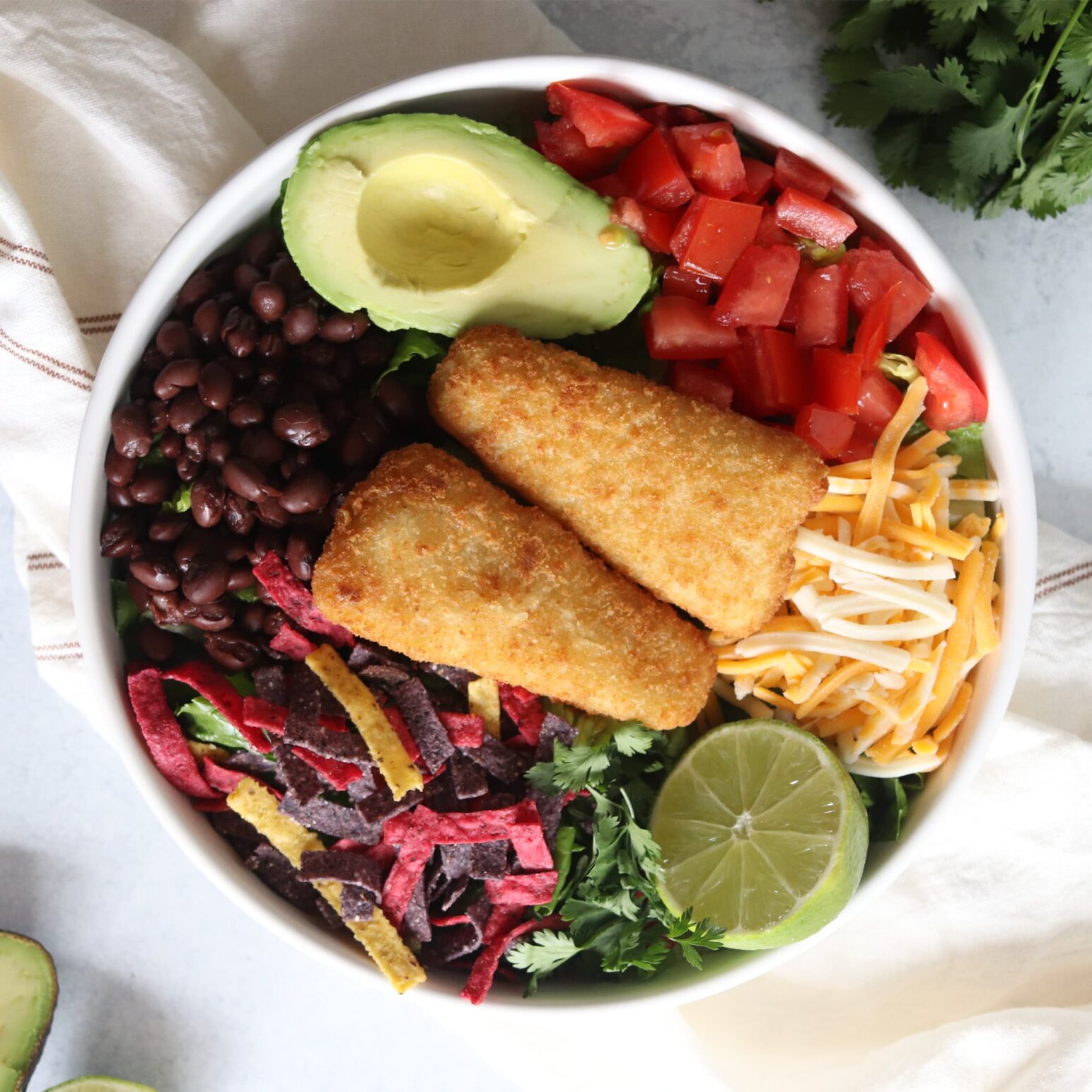 Bowl with two fish fillets and ingredients for tacos